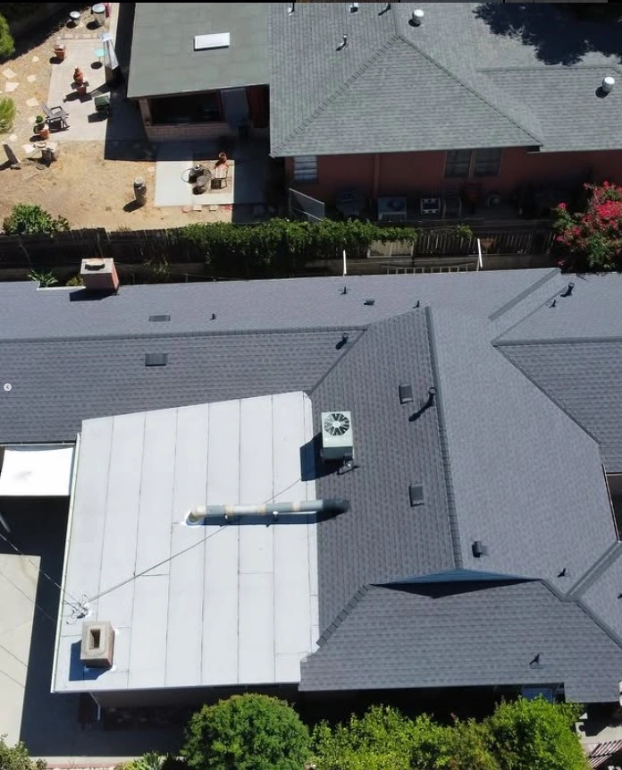 Aerial view of a recently completed roof replacement on a coastal home in Malibu, featuring asphalt shingles and a flat roof section.