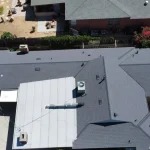 Aerial view of a recently completed roof replacement on a coastal home in Malibu, featuring asphalt shingles and a flat roof section.